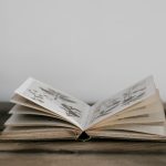 An open book with illustrated pages resting on a wooden table