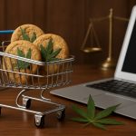 A small shopping cart filled with cannabis cookies alongside a laptop and a scale symbolizing law